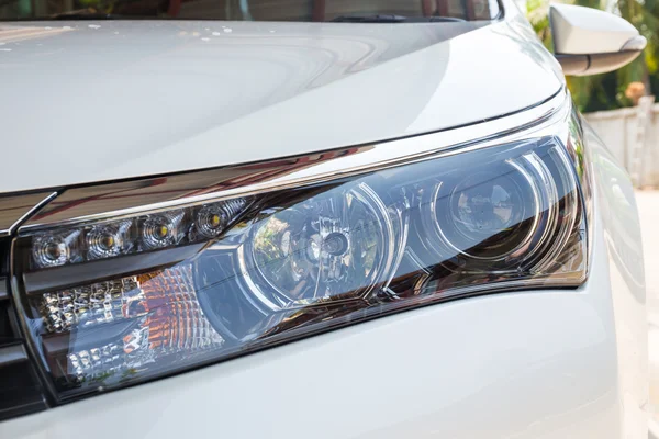 Closeup headlights of modern white car with LED daylight running lights