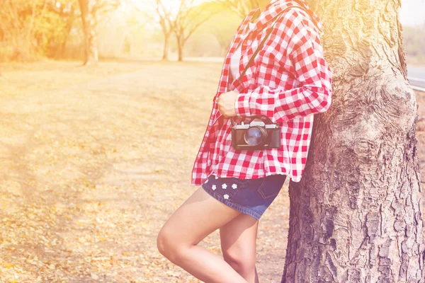 Tourist young woman holding vintage old photo camera in outdoor, pastel or vintage style color copy space background