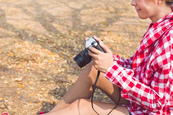 Tourist young woman holding vintage old photo camera in outdoor