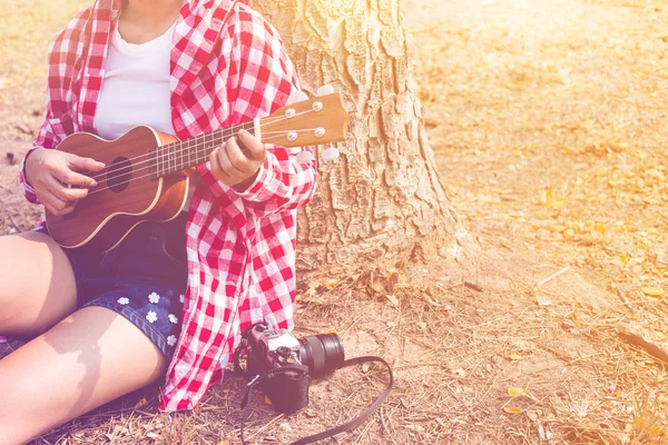 Beautiful asian women playing ukulele guitar at outdoor in pastel or vintage style color. copy space background