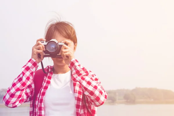 Young woman girl is travel with backpack and handle camera of take photos. travel concept in pastel or vintage style color. copy space background