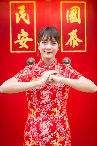 Happy Chinese new year. Cute Asian woman with gesture of congratulation isolated on red chinese pattern traditional background (text