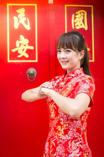 Happy Chinese new year. Cute Asian woman with gesture of congratulation isolated on red chinese pattern traditional background (text\
