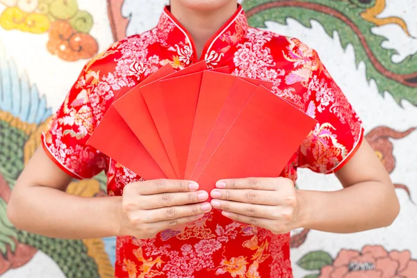 Happy chinese new year,Asian woman dress traditional cheongsam and qipao holding red envelopes ang pow or red packet monetary gift card on chinese pattern traditional background