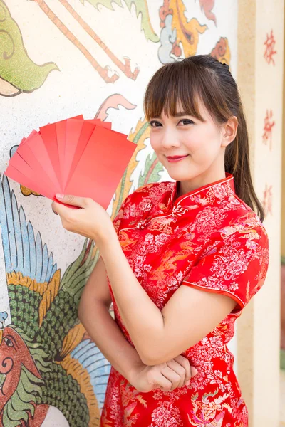 Happy chinese new year,Cute smiling Asian woman dress traditional cheongsam and qipao holding red envelopes ang pow or red packet monetary gift card on chinese pattern traditional background