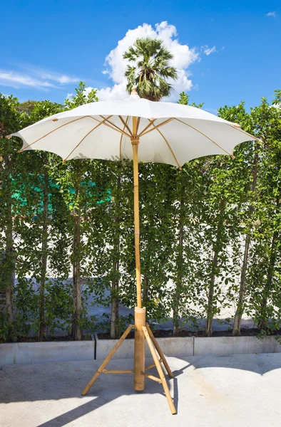 Wooden furniture covered by umbrella in garden and blue sky