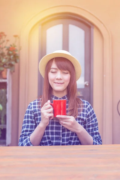 Wear hat woman sitting in outdoor with warm drink relax pastel color tone