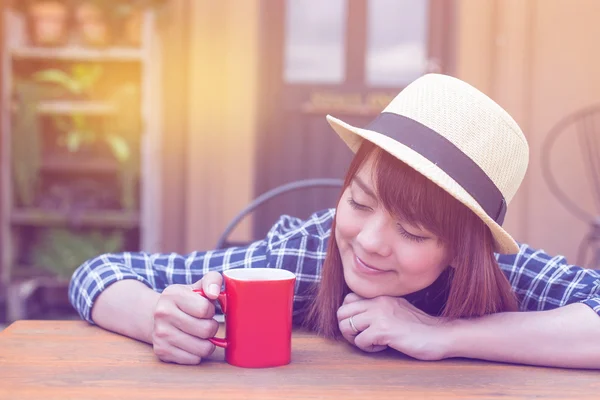Wear hat woman sitting in outdoor with warm drink relax pastel color tone