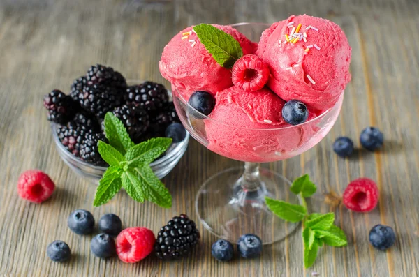 Red ice cream with berries, sorbet on wooden dark background