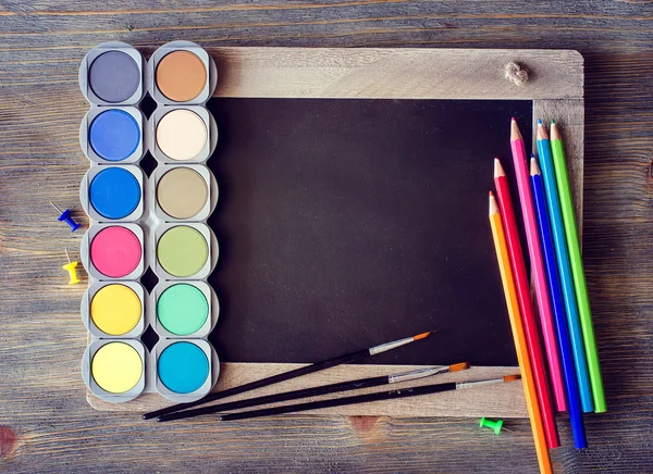 Blackboard with colored pencils, palette, aquarelle for painting