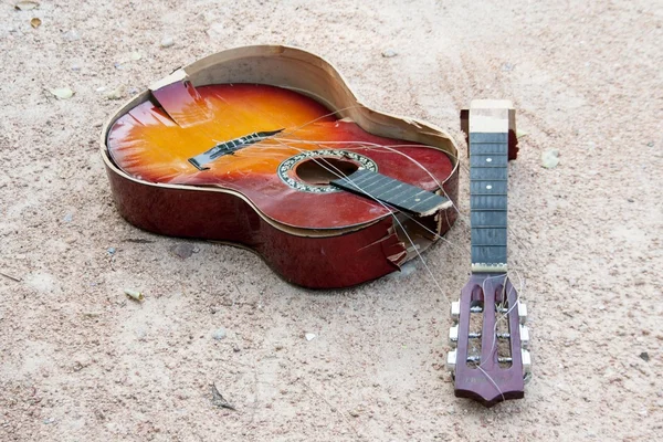 Broken guitar on sand