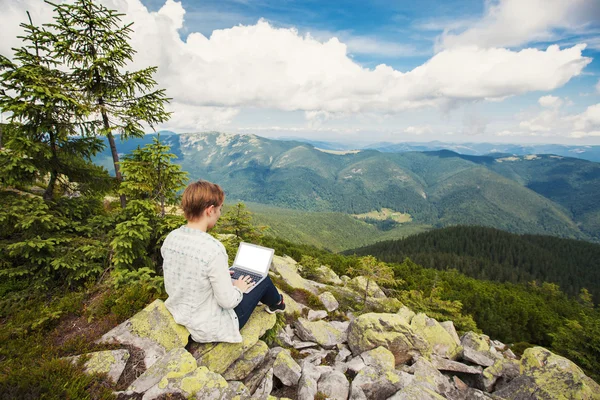 Woman working on laptop on the mountain