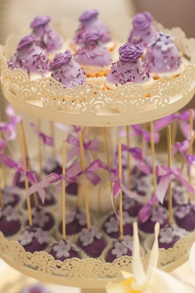 Candy Bar. Tray with delicious cakes. Elegant sweet table with big cake, cupcakes, cake pops on dinner or event party. Cake pops. Violet and White