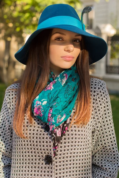 A beautiful brunette young girl posing in hat and coat. Young woman in autumn situation in the park