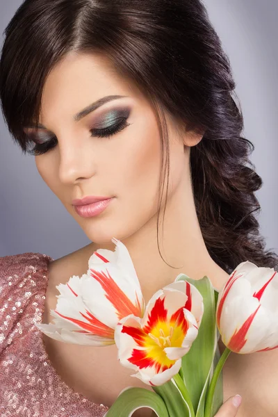 Spring beauty model studio shooting. Portrait of smiling young woman with flowers orange tulips on white background. Fashion fresh makeup. Sensual lips. Perfect skin. Tenderness. Romantic style