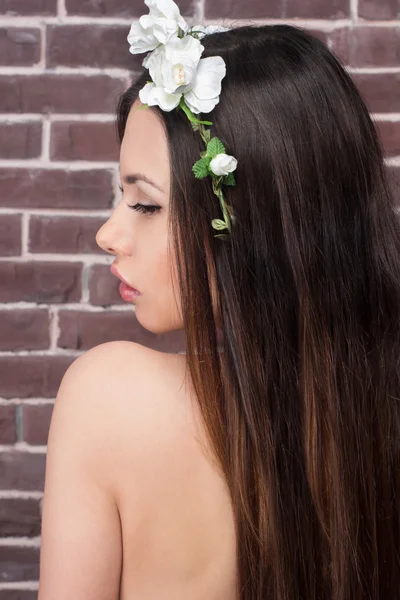 Beauty face of the young beautiful woman with white flowers in her hair. Fashion model with hairstyle and flowers in her hair