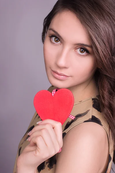 Portrait of Beautiful gorgeous smiling woman with glamour bright makeup and red heart in hand. Valentine\'s Day. Beautiful smiling woman with a gift in the form of two heart in his hands.
