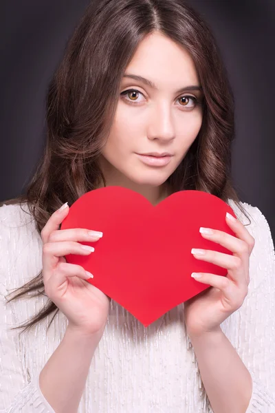Portrait of Beautiful gorgeous smiling woman with glamour bright makeup and red heart in hand. Valentine\'s Day. Beautiful smiling woman with a gift in the form of two heart in his hands.