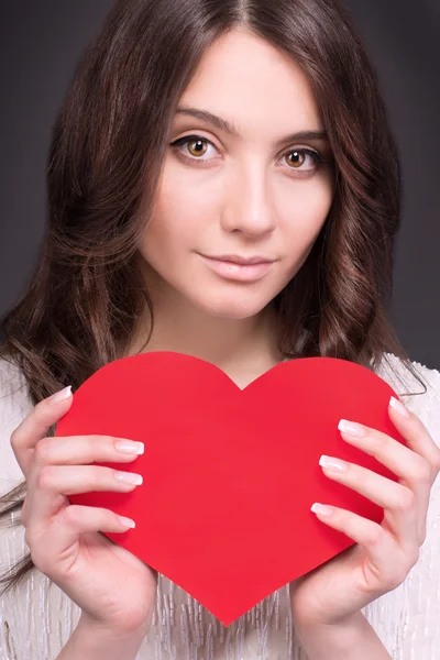 Portrait of Beautiful gorgeous smiling woman with glamour bright makeup and red heart in hand. Valentine\'s Day. Beautiful smiling woman with a gift in the form of two heart in his hands.