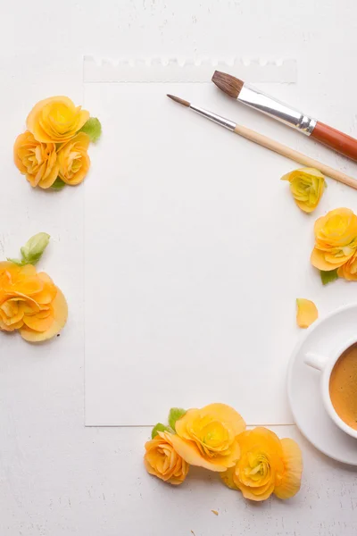 Blank notepad, flowers, brushes and cup of coffee over white woo