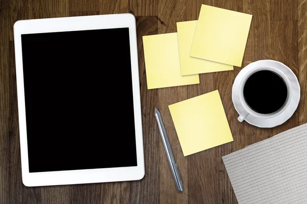 Digital tablet computer with sticky note paper and cup of coffee on old wooden desk. Simple workspace or coffee break with use of web .