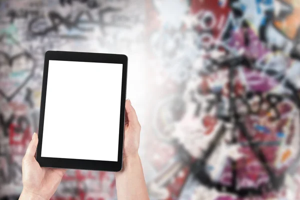 Tablet in the hands of women and graffiti in the background