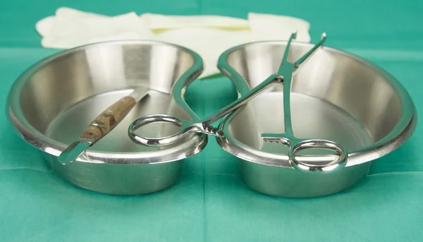 Surgical clamp and knife placed on kidney shape bowl