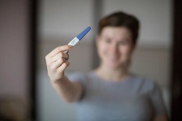 An image of a pregnant woman holding the positive test