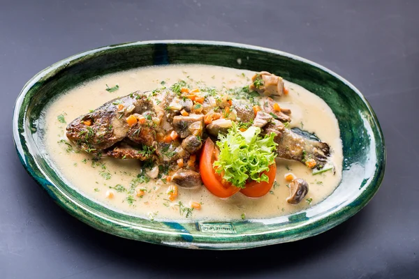 Seabass fish baked with vegetables, herbs and lemon, close-up