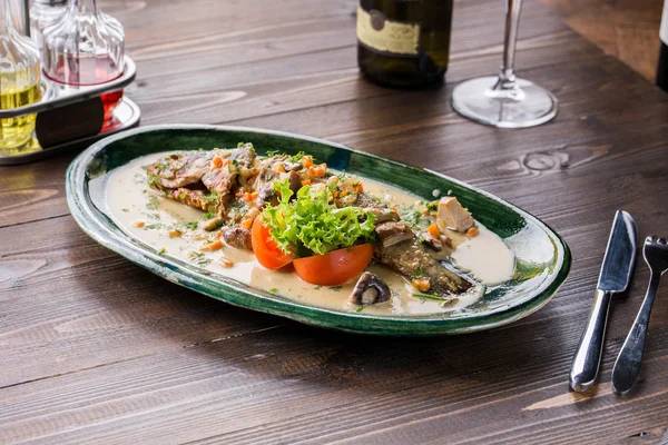 Seabass fish baked with vegetables, herbs and lemon, close-up