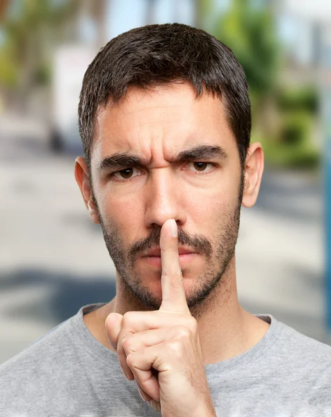 Close up of a young man with silence gesture