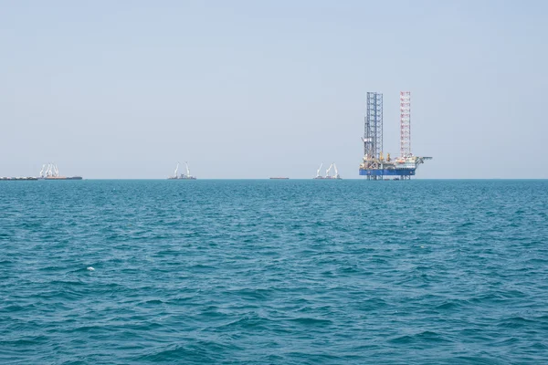 Oil rig drilling platform in large Pacific Ocean on cloudless sk