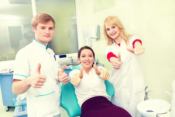 Woman giving thumbs up at dentist office.