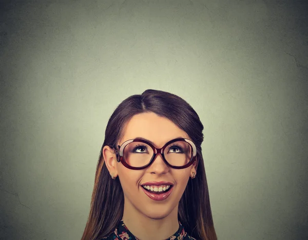 Happy woman looking up wondering isolated on gray wall backgroun