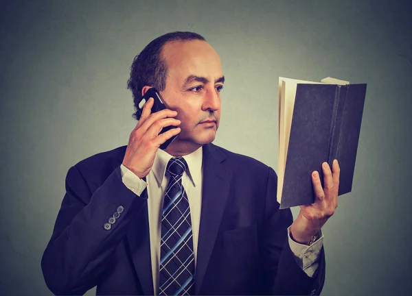 Business man in suit, executive reading book talking on smart phone