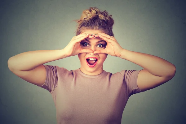 Surprise. Stunned curious woman peeking looking through fingers like binoculars