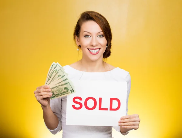 Successful business woman holding sold sign and cash dollar bills. Financial reward