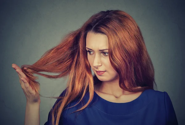 Upset frustrated young woman surprised she is losing hair, noticed split ends