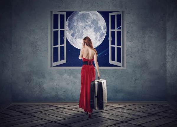 Beautiful woman in red dress walking to opened window with moon