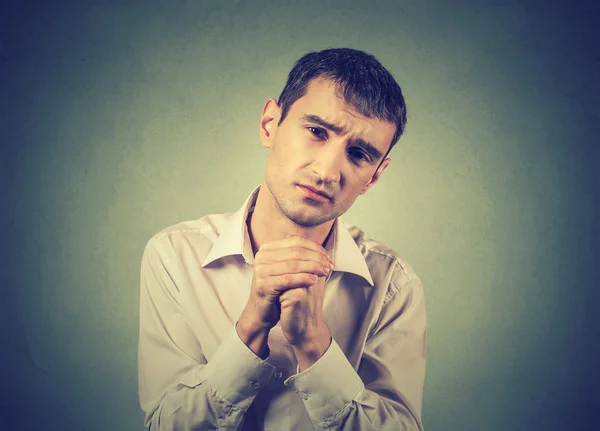 Desperate young man showing clasped hands, please forgive me