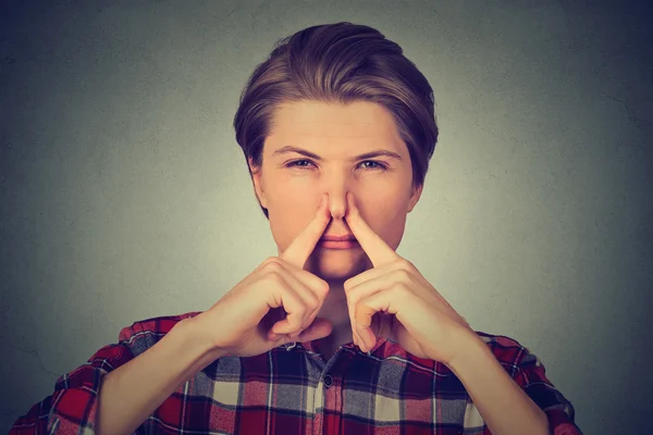 Disgusted man pinches nose with fingers something stinks bad smell