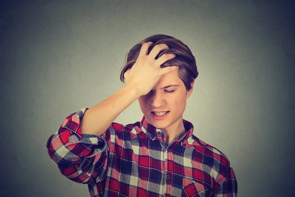 Silly young man, slapping hand on head having a duh moment