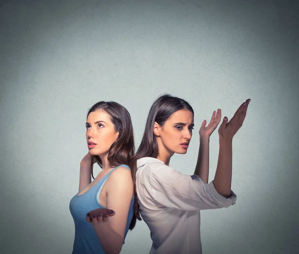 Two women back to back putting hands in air looking up in frustration