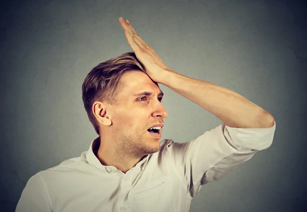 Silly man, slapping hand on head having duh moment regrets