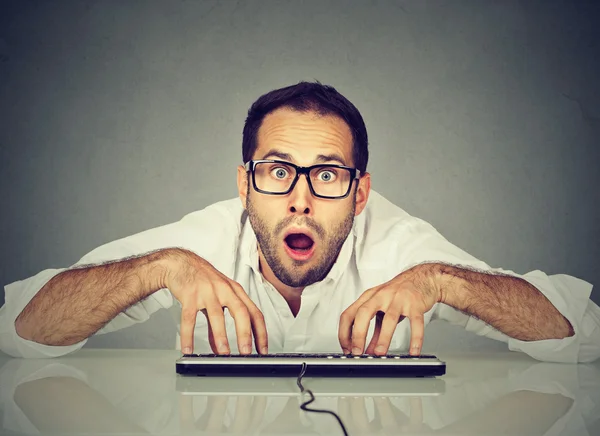 Crazy nerdy looking man in glasses typing on keyboard