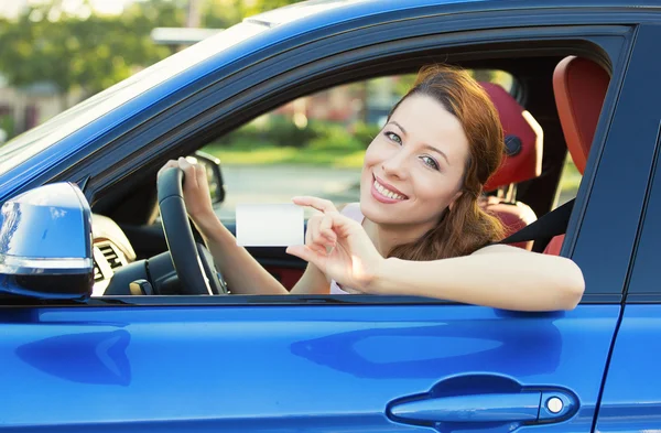 Woman in new car showing blank drivers license