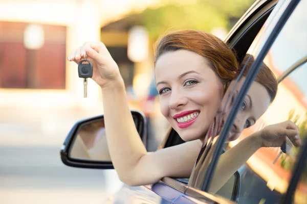 Happy woman, buyer sitting in her new blue car showing keys