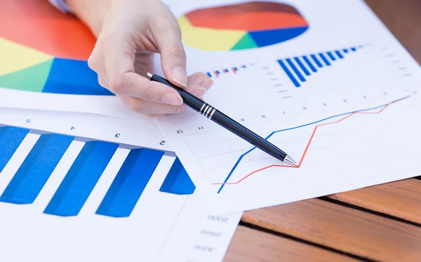 Female hands pointing with pen at business financial report graphic