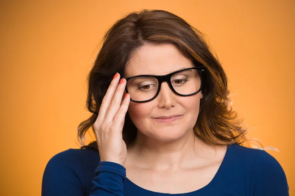 Mature, shy, sad woman playing nervously with glasses