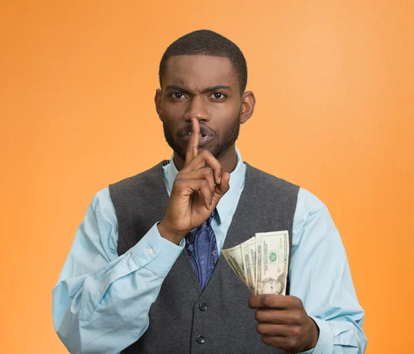 Corrupt businessman holding dollar bills in hand showing shhh sign